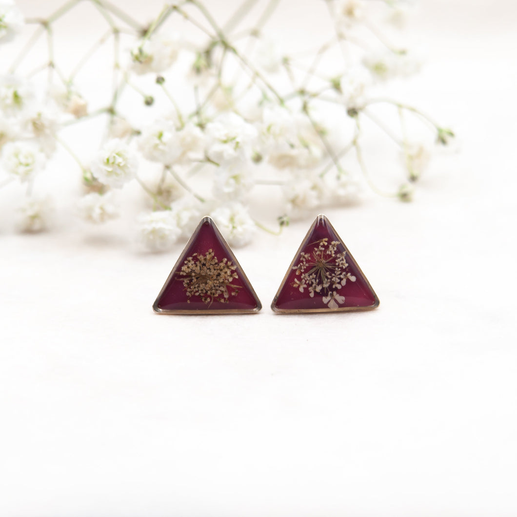 Triangular earrings in resin with wild carrot flower on a pink background